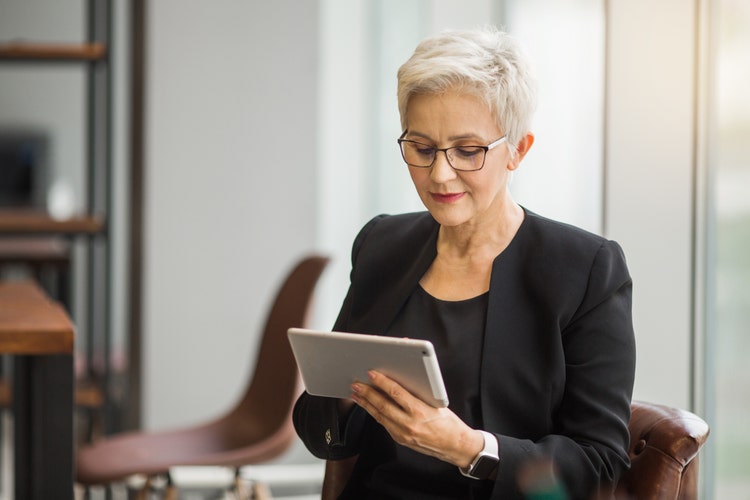 A woman uses a tablet to view a customer payment received from a recurring invoice.