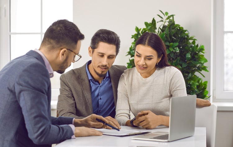 A couple review a contract for deed agreement with a real estate agent.