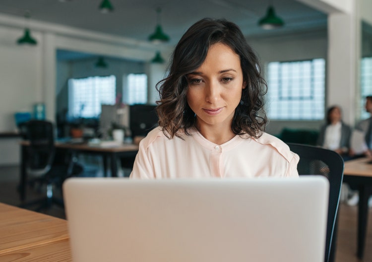 A woman in an office uses her laptop to sign a one-way NDA.