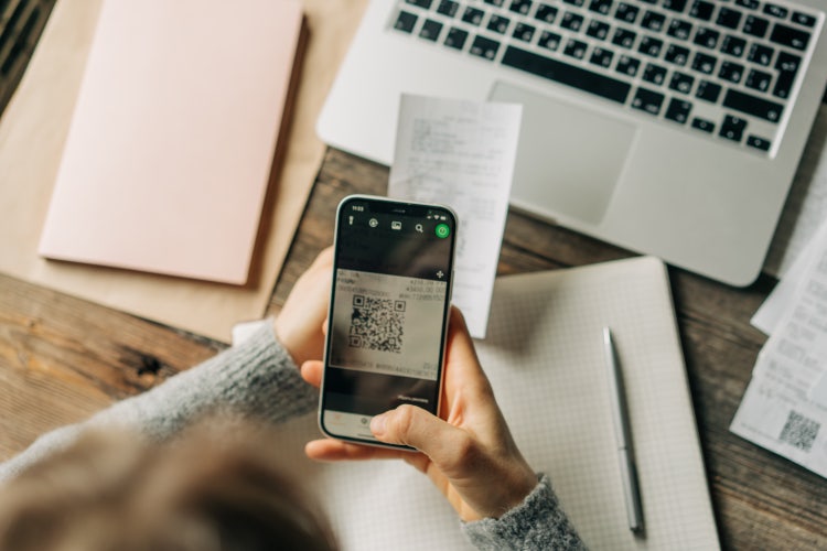 A person uses their smartphone to scan a QR code with an invoice app