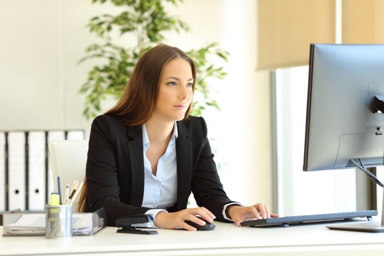 A woman writes a letter of reprimand on a desktop computer