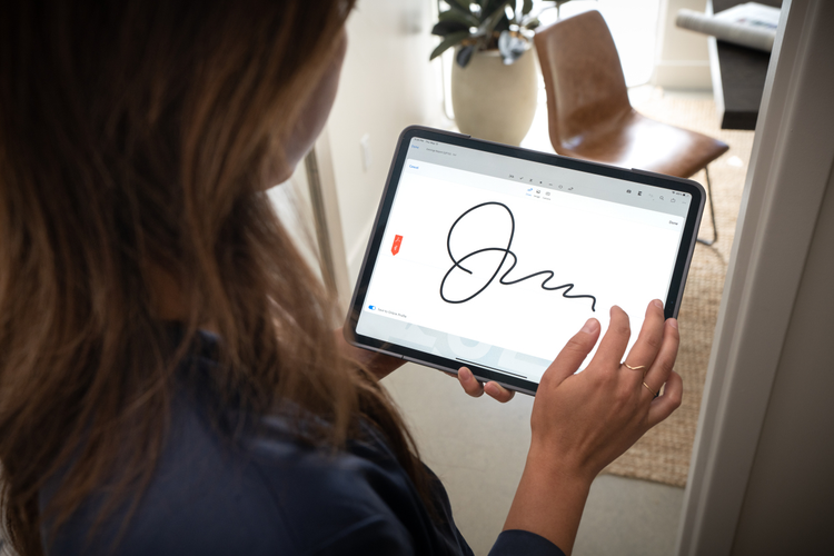 A woman e-signs a document on a tablet.
