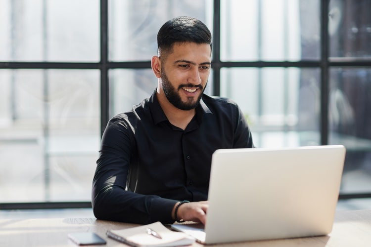 A man uses his laptop to learn about the budget approval process.