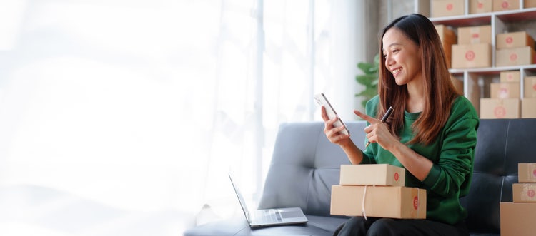 A woman uses her phone to review a sales receipt for her business.