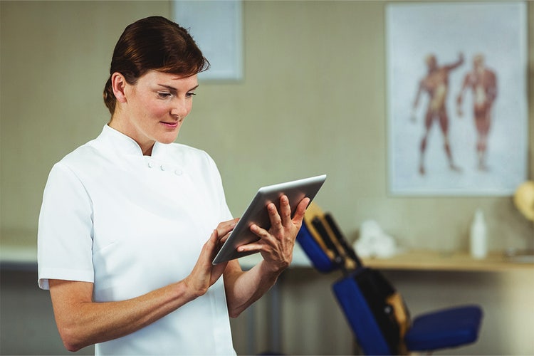 A woman creates an invoice for massage therapy on a tablet.