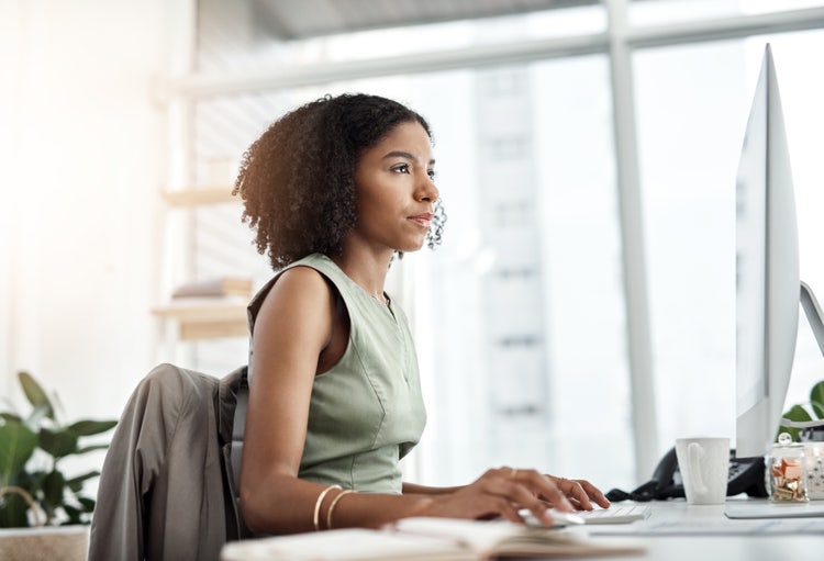 A woman in an office uses her computer to research the differences between a contract rider vs addendum.