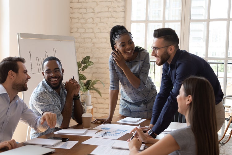 A group of people in a conference room meet to discuss how to improve interdepartmental collaboration.