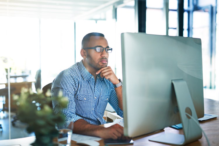 A man in an office uses his computer to look at the difference between an invoice versus a contract.