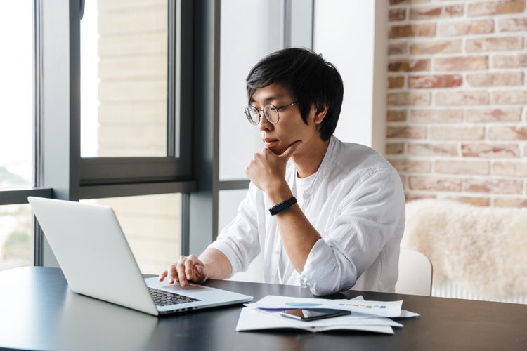 A man uses his laptop to research whether invoices need to be signed.