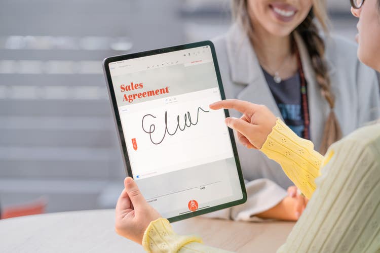 A woman holding a tablet with an e-signature on it.