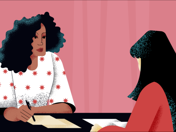 A woman sits across from another woman, taking notes on a piece of paper.