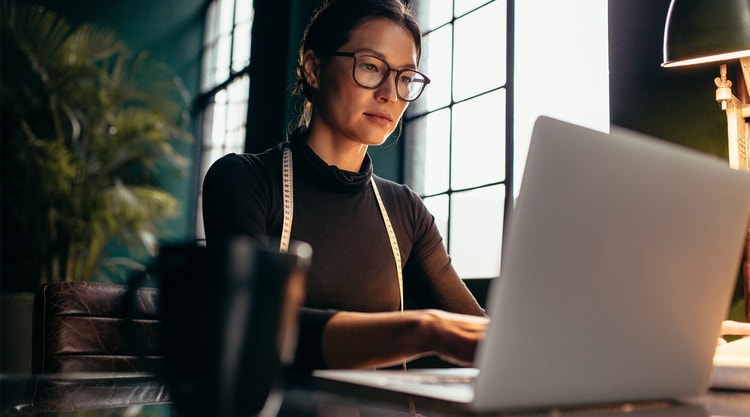A person sitting at a desk using their laptop.