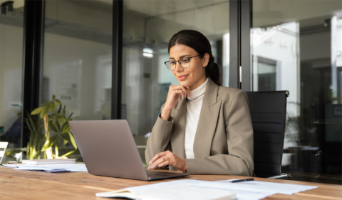 A woman in an office happily reviews a sales contract.