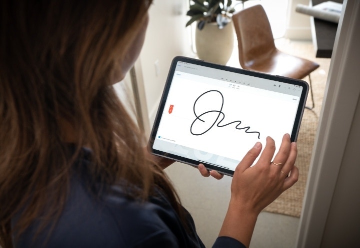 A photo of a borrower digitally signing a collateral loan agreement using Adobe Acrobat Sign.
