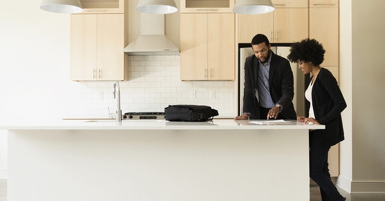 Two people reviewing a sublease agreement on a countertop in a kitchen