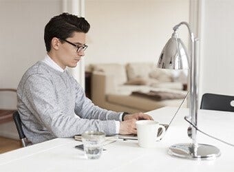A person sitting at their kitchen counter using a laptop