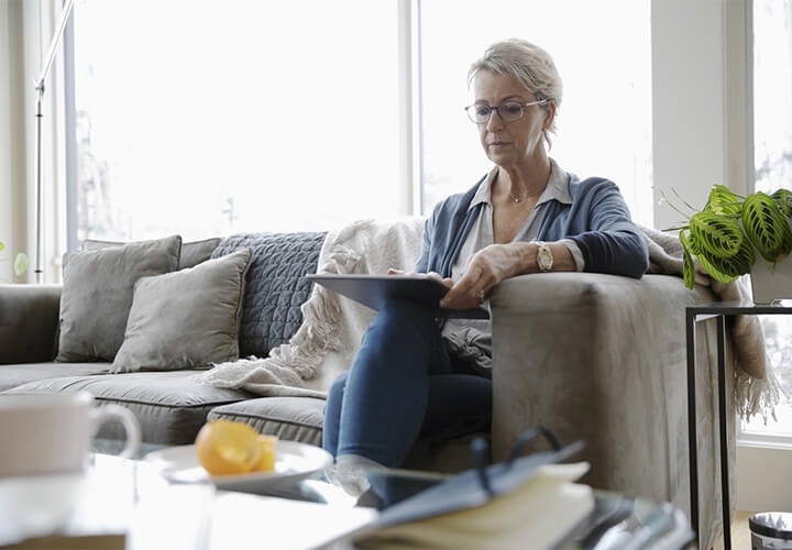 A homeowner reviewing a mortgage note on their tablet while sitting on a couch