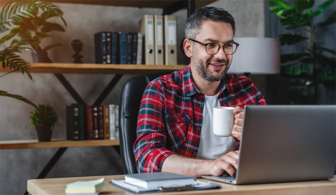 A landlord smilingly reviews rental applications on his laptop.