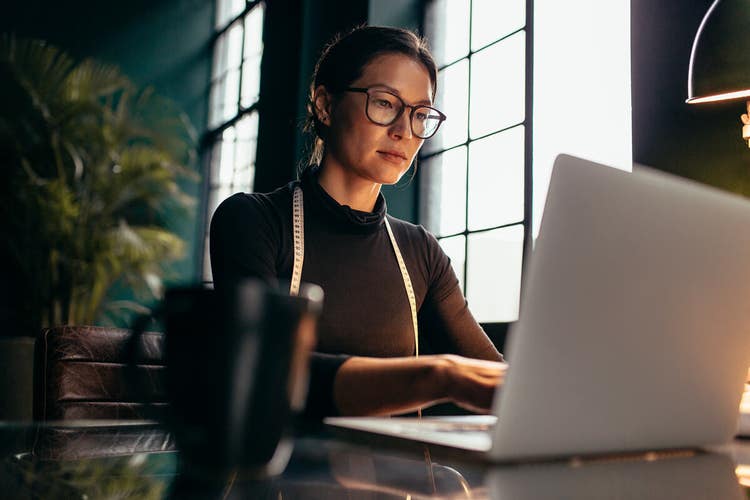 A person sitting at a desk using their laptop.