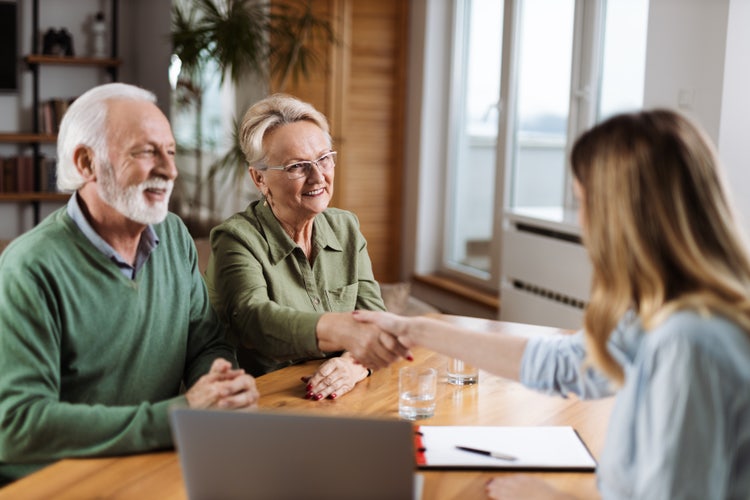 A man and woman review the terms of a real estate purchase agreement with their real estate agent together.
