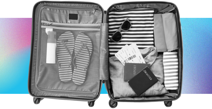 An open suitcase with flip flops, sunglasses, plane tickets, a passport, and other travel essentials.