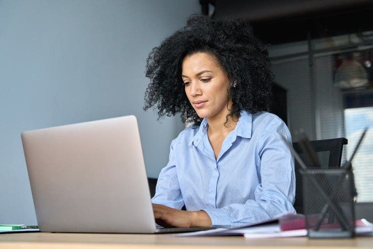 A woman sitting at a desk changes the font size in a PDF from her laptop.