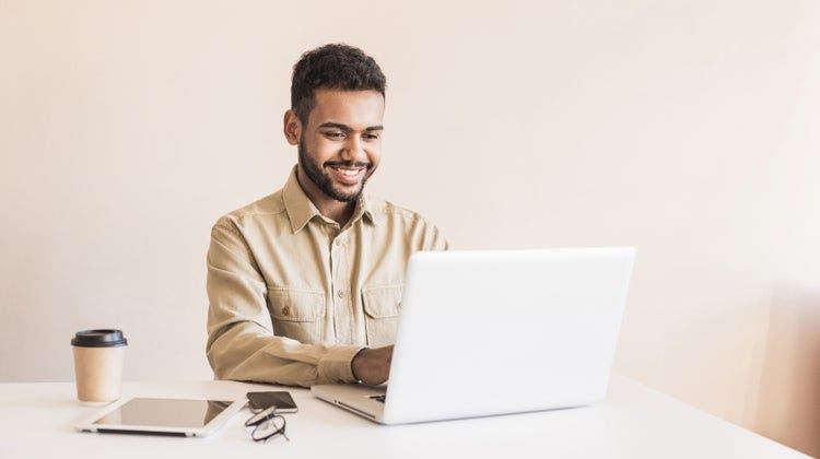A man in an office uses his laptop to insert a PDF into a PowerPoint presentation.