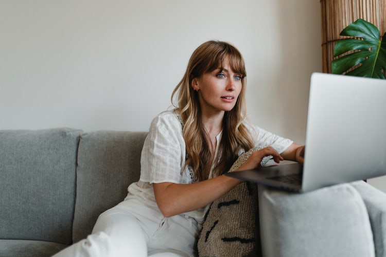 A woman in a living room works on her computer without an internet connection.
