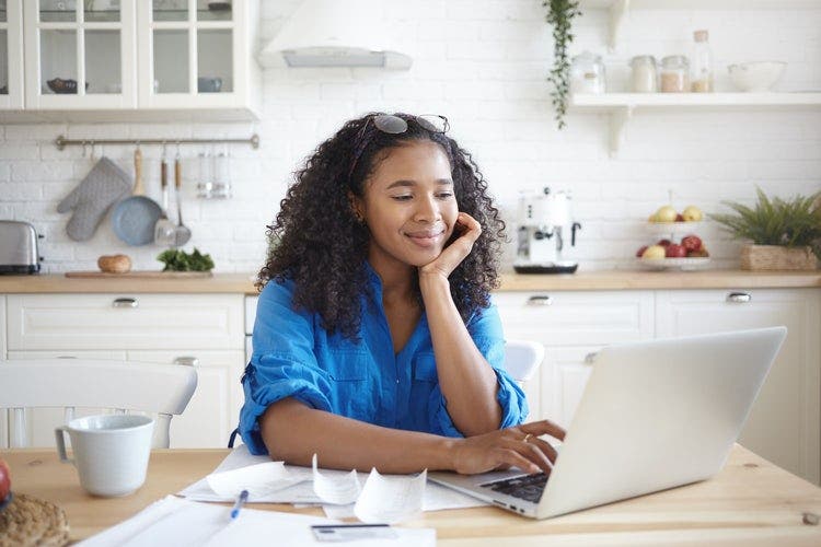 A woman in a kitchen uses her laptop to convert a JPG to an Excel file.