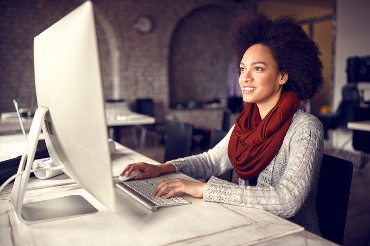 A woman wearing a red scarf sitting at a desktop computer sharing a PDF on Facebook Messenger.