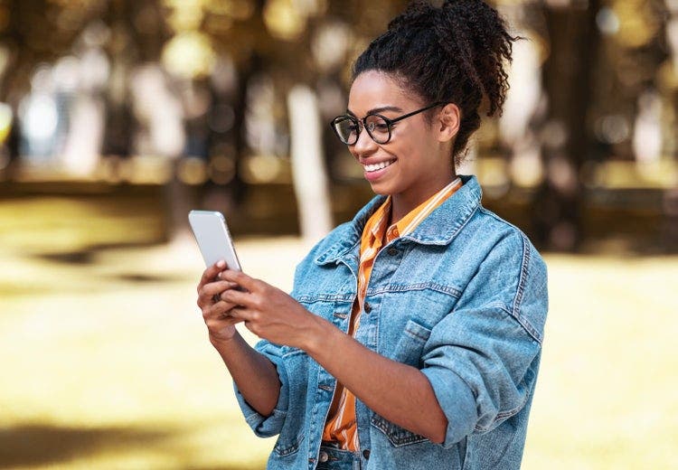 A smiling woman stands outdoors using an iPhone to reorder PDF pages.