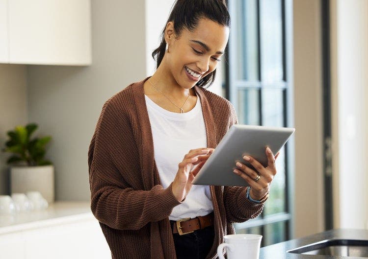 A person standing in a kitchen using a tablet to add notes to a PDF.
