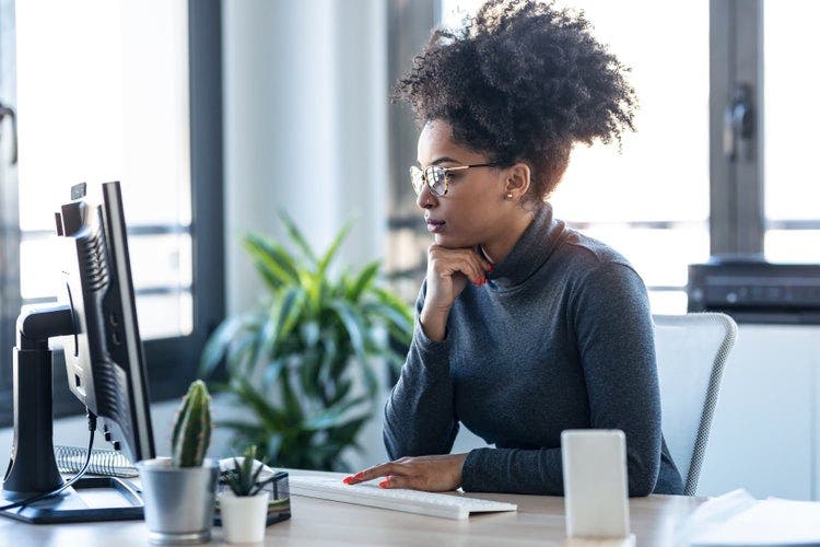 A young black woman using a desktop computer to compress a PDF in Linux to reduce file size.