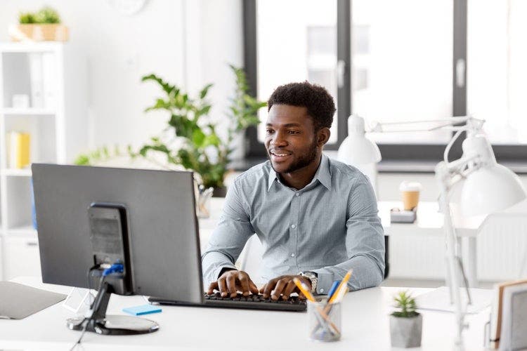 A man in an office converts a PDF to a PNG file on his computer.