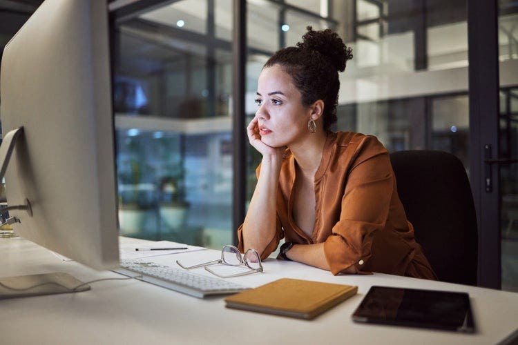 A woman sitting at a desk saves a PDF on her computer.