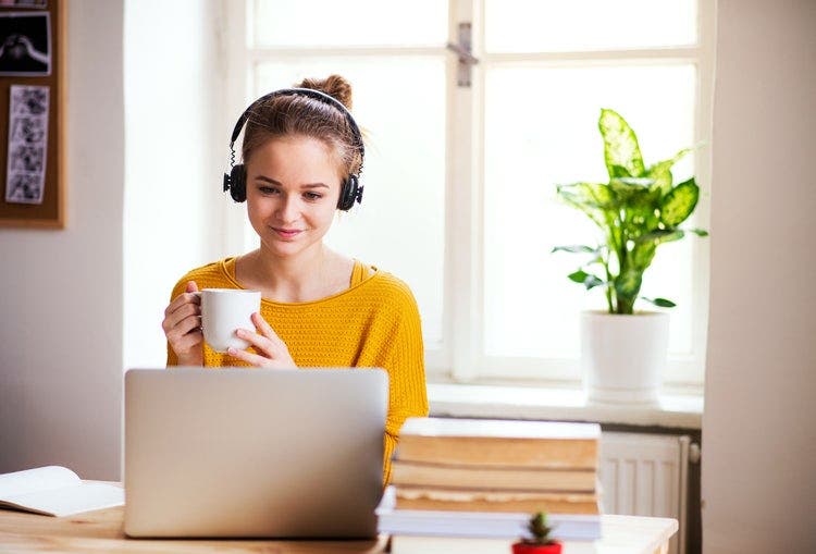 A woman sips coffee and has PDF files read aloud to her from a laptop.