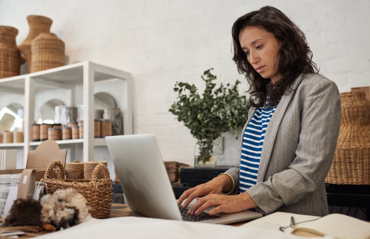 A woman uses her laptop to learn how to go paperless for her small business.