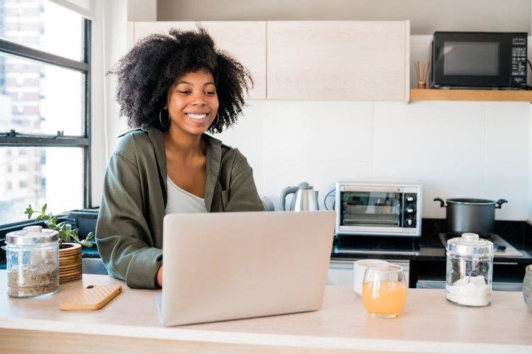 A woman in a kitchen converts Outlook emails into PDF files using her laptop.