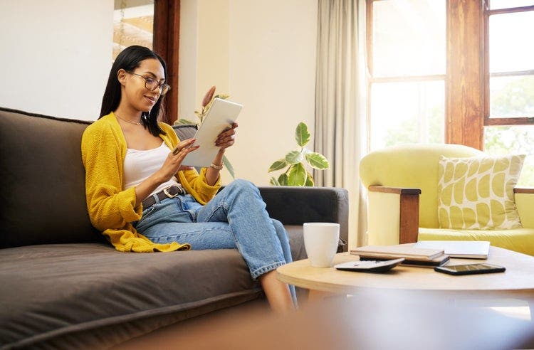 A woman sitting on a couch reorders PDF pages on an iPad.