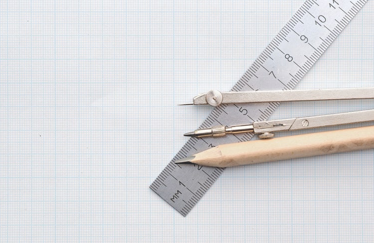 A pencil, compass, and ruler on graph paper.