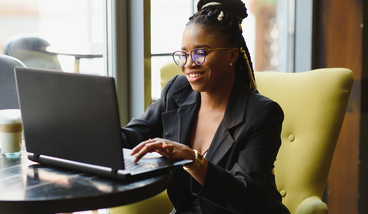 A woman sitting at a table types on a laptop.
