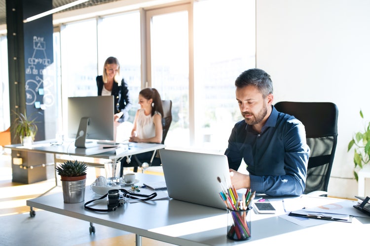 A group of employees collaborating on a task list at a desk in an office.