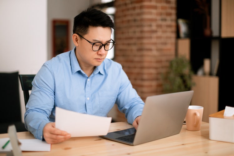A man uses his laptop to go through his tax transcript.