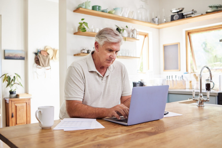 A man learns how to write a bill of sale for a boat on his laptop using Adobe Acrobat.