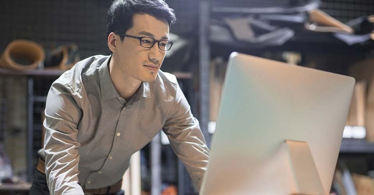 A person standing in front of a computer reviewing digital documents
