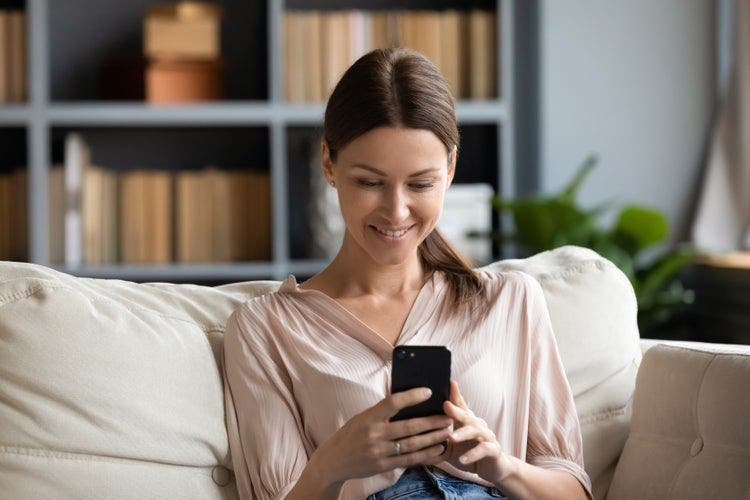 A woman in a living room uses her iPhone to share a PDF.