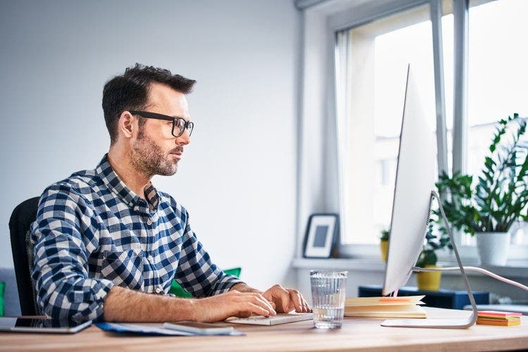 A man prints a PDF on a Mac desktop computer.