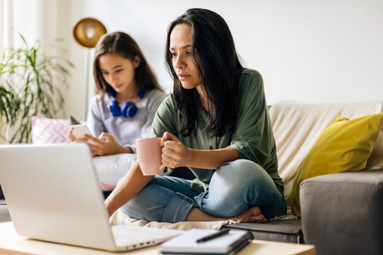 A mother uses her laptop to write an absent letter for school for her daughter.