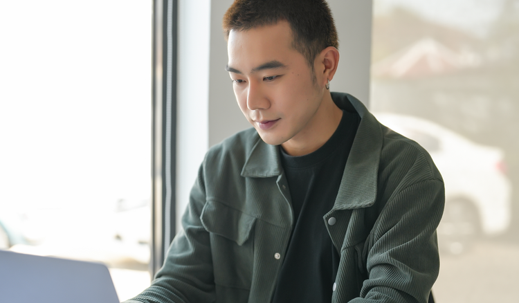 Man sits in front of a laptop and redacts a PDF.