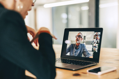 A businesswoman manages a hybrid team through a video conference meeting.